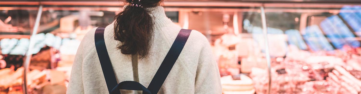 une cliente devant un étal de boucherie.
