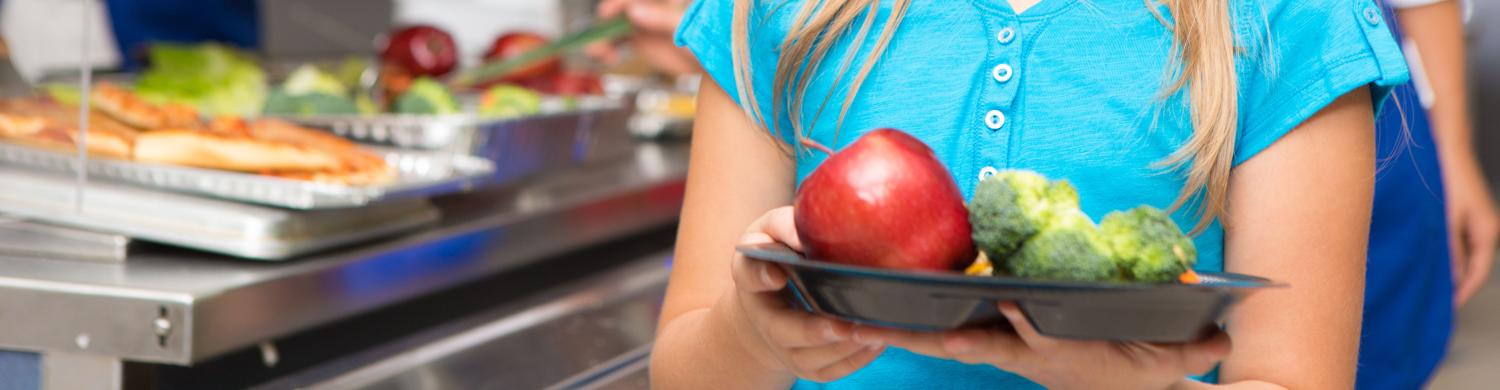 une enfant dans une cantine scolaire avec des légume