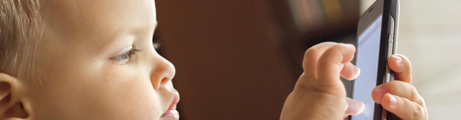 un jeune enfant joue sur un téléphone portable