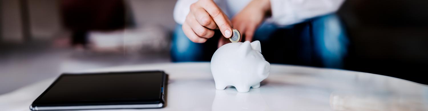 Une personne met une pièce dans une tirelire
