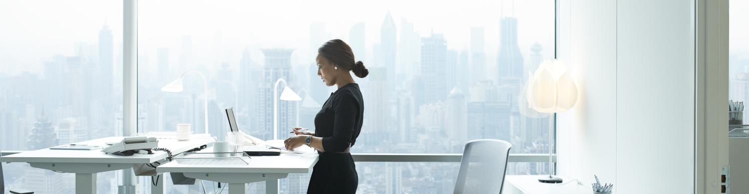 une femme travaille debout sur un bureau surélevé