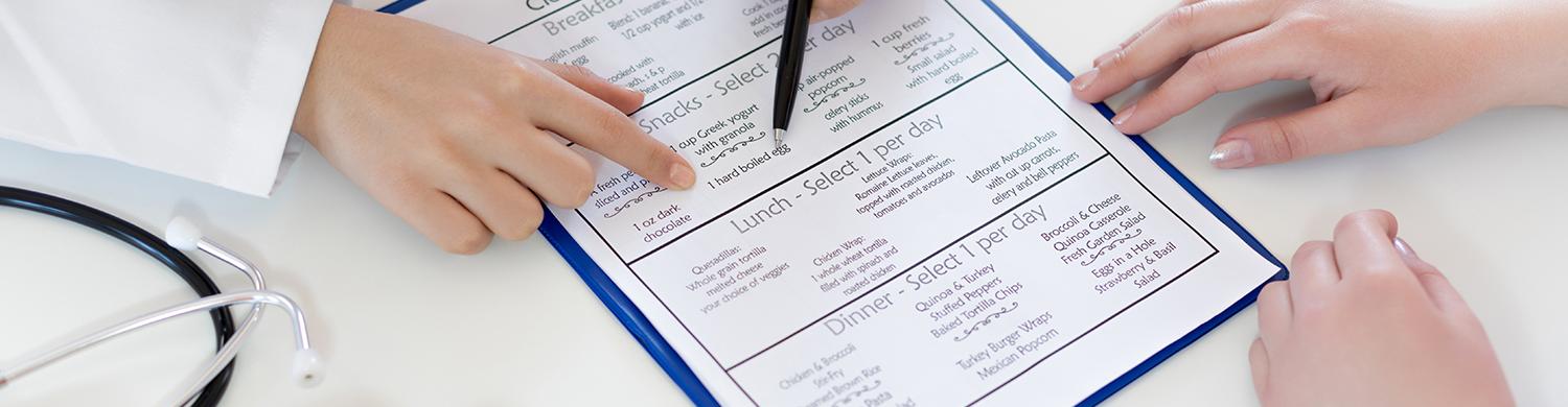 des mains qui pointent un document, une corbeille de fruits à côté