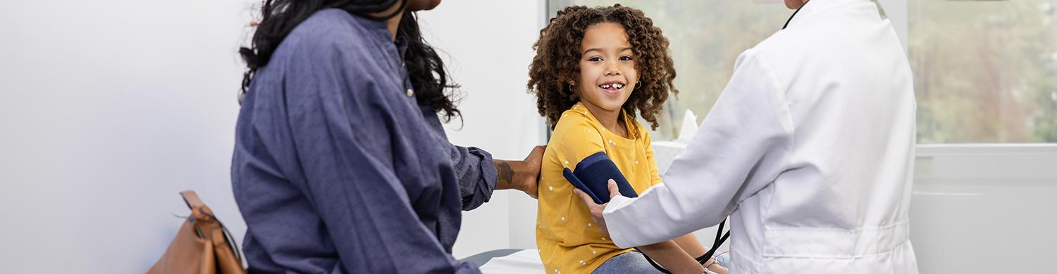 Un médecin qui prend la tension d’un enfant accompagné de sa mère