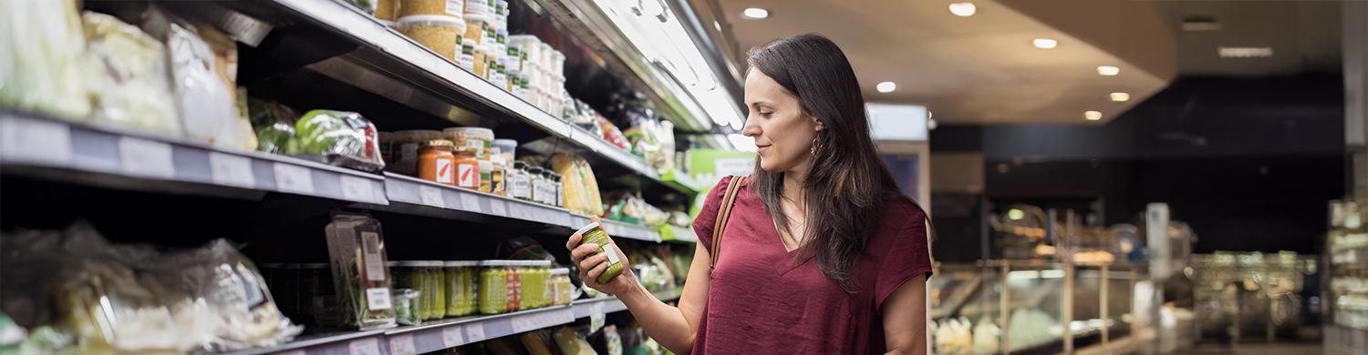 femme regardant un produit dans un rayon de supermarché