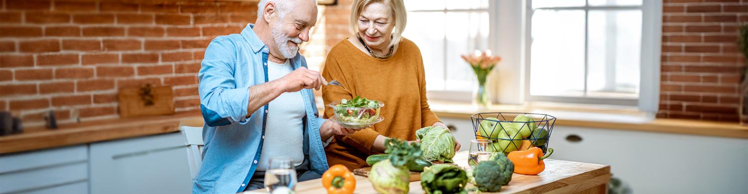 couple de personnes âgées cuisinant des légumes