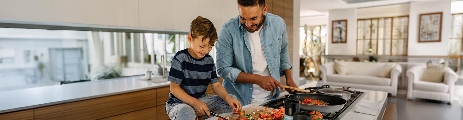 a man and a child cooking vegetables