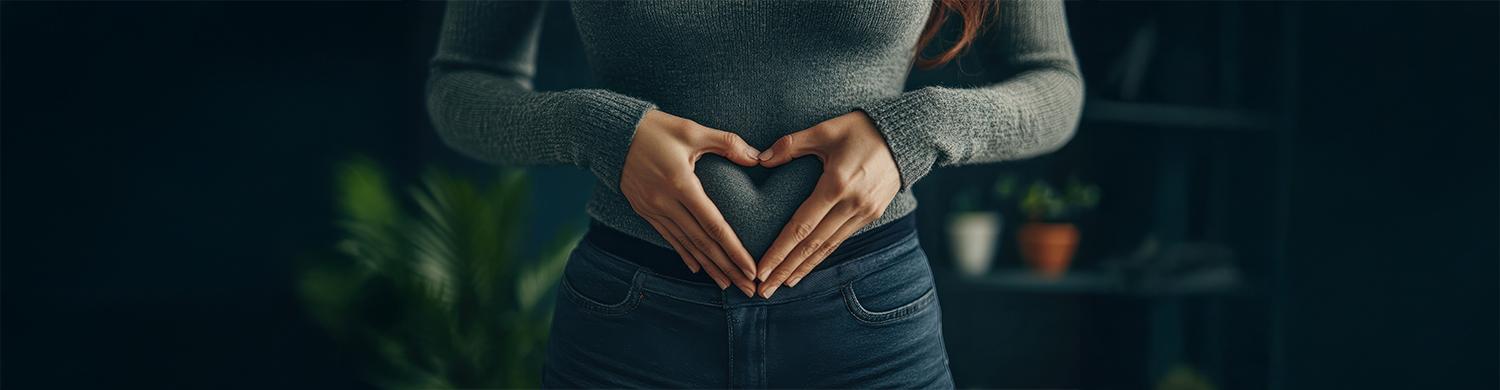 femme tient ses mains en cœur sur son ventre