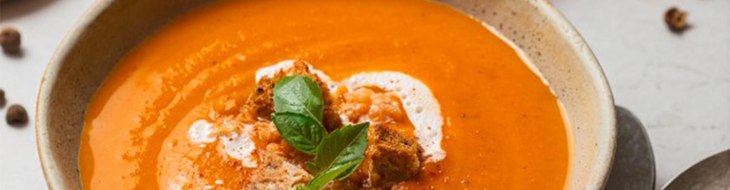 Bol de soupe tomate et lentille carottes avec des cuillères posé sur une table