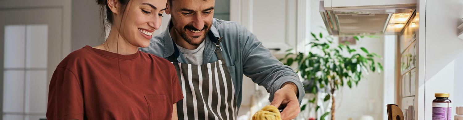 Couple cuisinant un plat préparé à la maison à base de pâtes