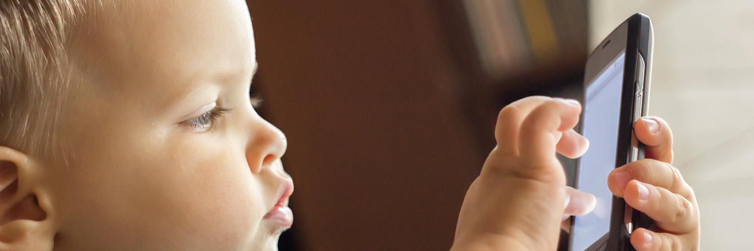 un jeune enfant joue sur un téléphone portable