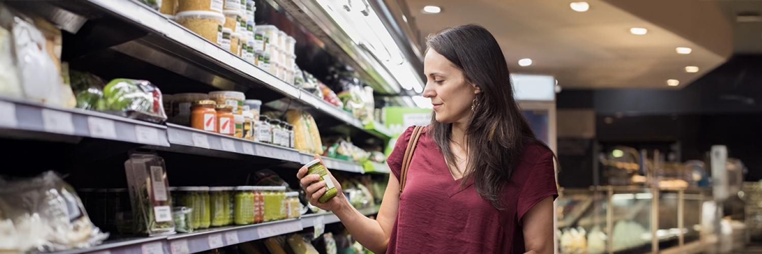 femme regardant un produit dans un rayon de supermarché