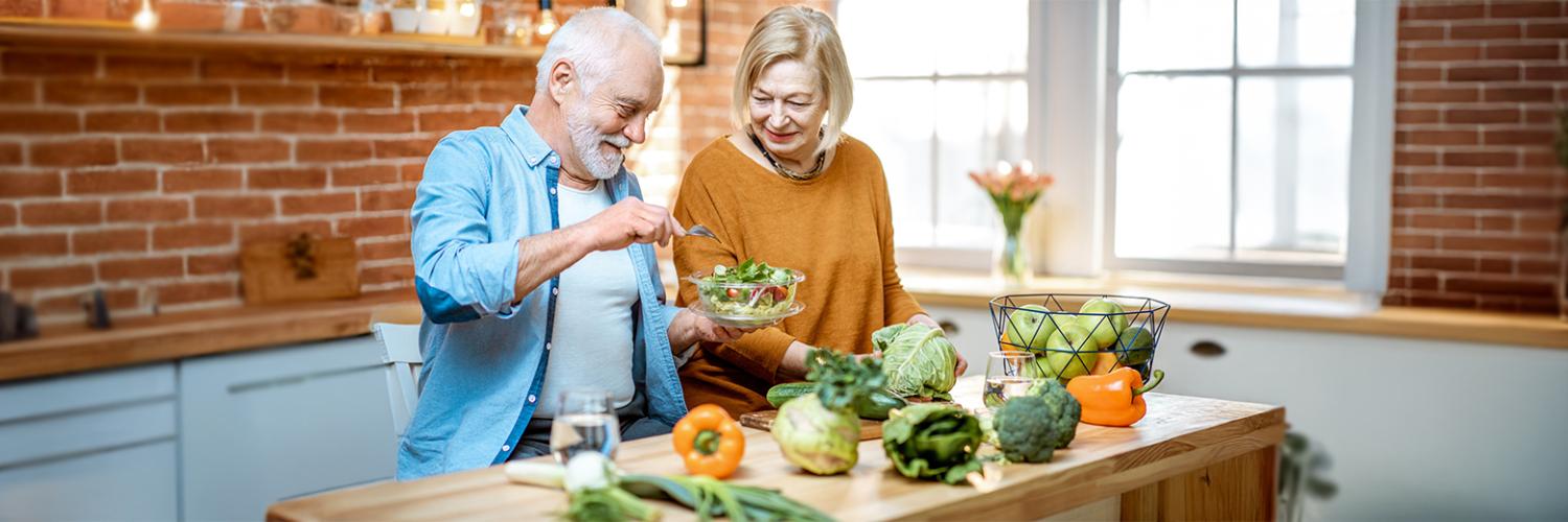 couple de personnes âgées cuisinant des légumes