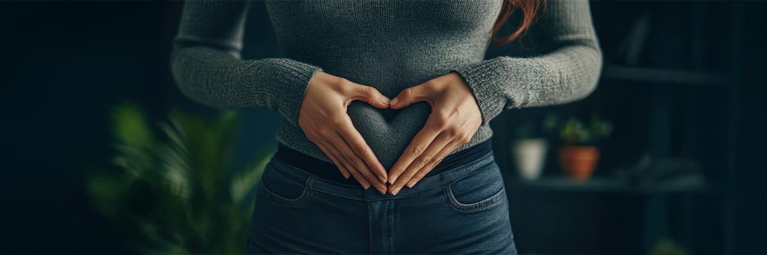 femme tient ses mains en cœur sur son ventre