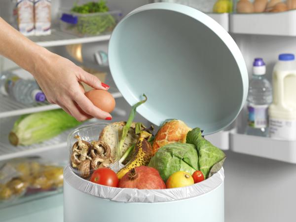 Une personne jette des denrées alimentaires dans une poubelle