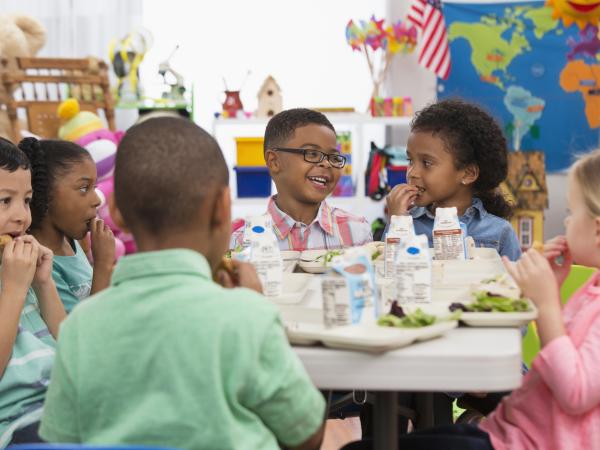 des enfants en train de déjeuner dans une cantine, souriants