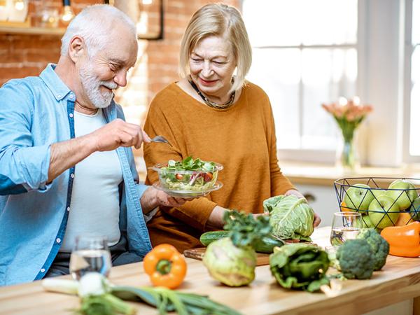 couple de personnes âgées cuisinant des légumes