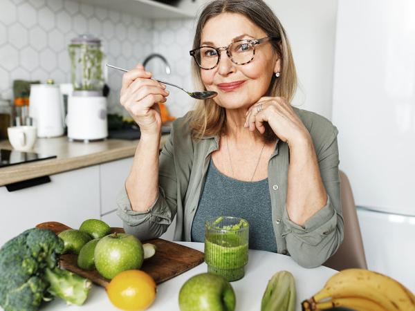 femme âgée en train de manger des fruits et légumes 