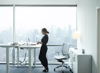 une femme travaille debout sur un bureau surélevé