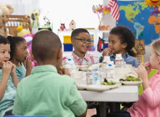 des enfants en train de déjeuner dans une cantine, souriants