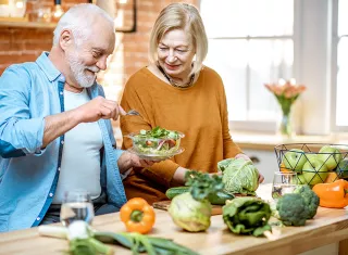 couple de personnes âgées cuisinant des légumes