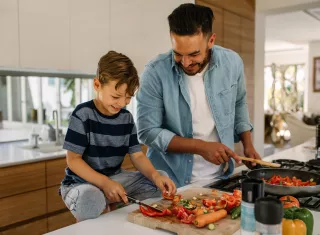 a man and a child cooking vegetables