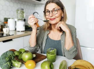 femme âgée en train de manger des fruits et légumes 