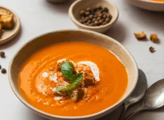 Bol de soupe tomate et lentille carottes avec des cuillères posé sur une table