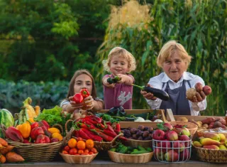 3 personnes avec des fruits et légumes sur une table