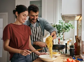 Couple cuisinant un plat préparé à la maison à base de pâtes